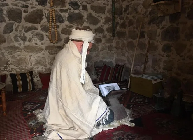 Kapalı bir mekânda kitap okuyan dervişhane figürü