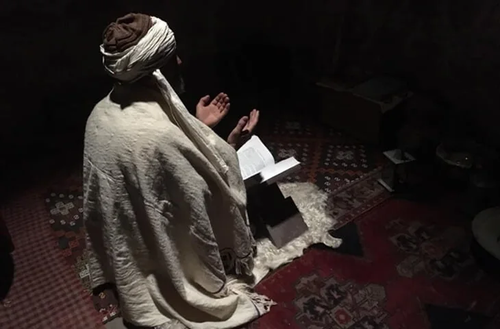 Karanlık bir odada namaz kılan figür